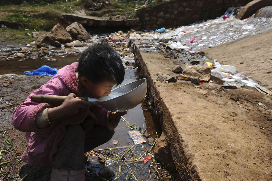 Un enfant boit de l’eau d’un ruisseau dans le comté de Fuyuan, province du Yunnan
